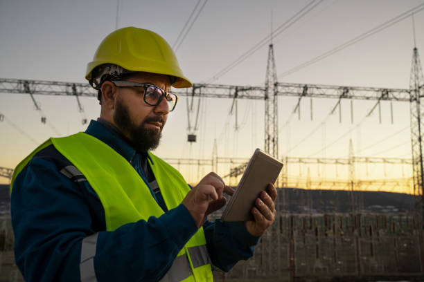 istock Engineer with tablet at an electrical power station checking equipment at sunset for maintenance. 2194055226