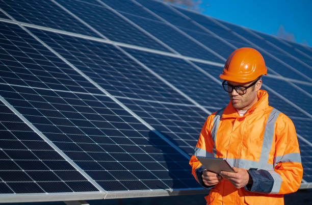 istock Engineer in orange jacket inspects large solar panels under clear blue sky backdrop, sunny day. 2194055247