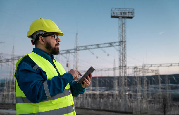 istock Engineer with tablet at an electrical power station checking equipment at sunset for maintenance. 2194055272