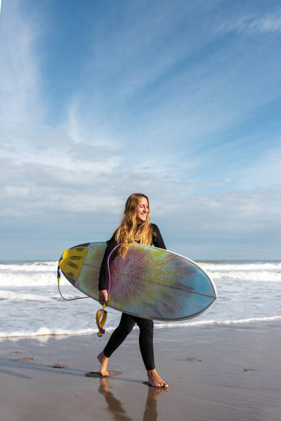 istock Woman with surfboard walking on wet beach 2194055788
