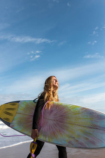 Photo of a young woman in the ocean, during her first surfing lessons
