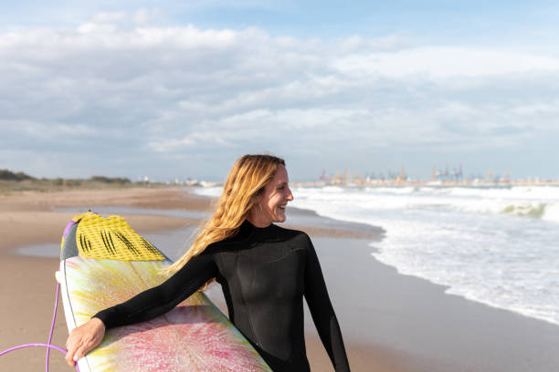 istock Woman with surfboard standing on wet beach 2194056100