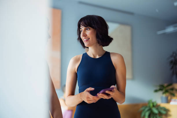 Confident Woman Using Phone in Stylish Fitness Studio