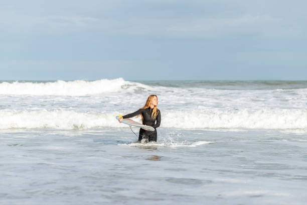 istock Woman with surfboard in sea 2194056473