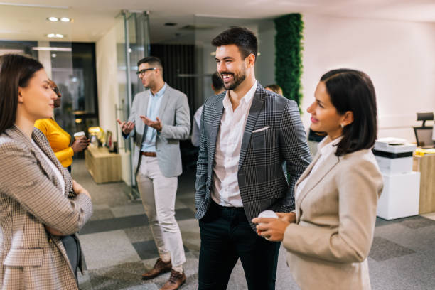 Business people on a coffee break during a seminar. Standing in the office and talking about the job.