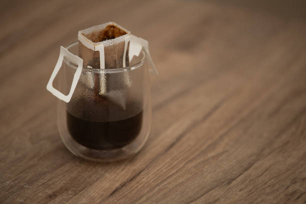 Freshly made drip coffee sits in a transparent glass container with a coffee filter, highlighting rich colors against a warm wooden backdrop, ideal for a comforting morning ritual.