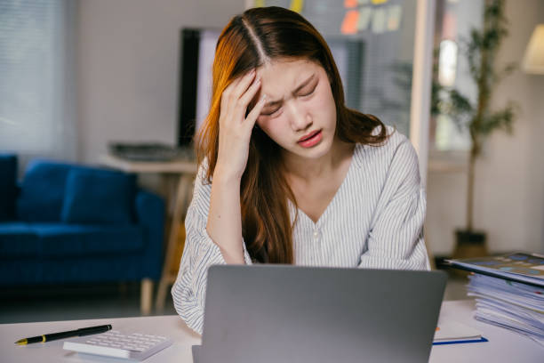 istock Stressed asian businesswoman sitting at a desk, experiencing a headache while working on a laptop in the office, feeling overwhelmed by work-related pressure and burnout 2194059402