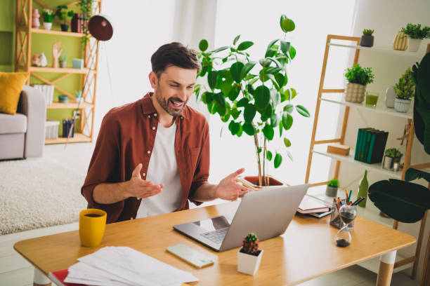 istock Smiling young man engaged in a joyful video call from his home, surrounded by stylish decor and greenery indoors 2194059709