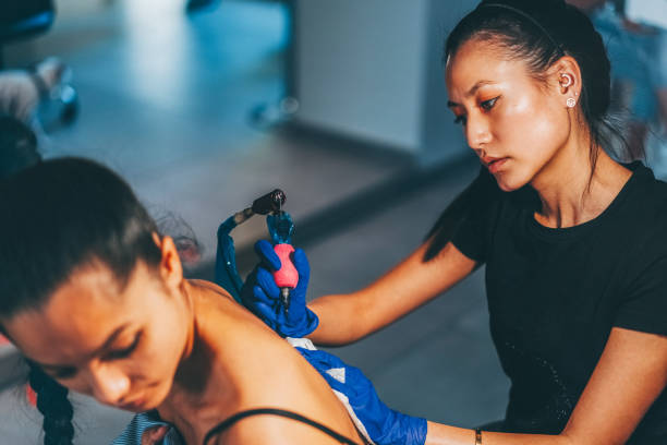 Tattoo artist drawing new tattoo on woman’s back