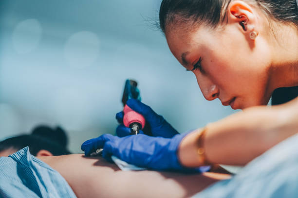 Tattoo artist drawing new tattoo on woman’s back
