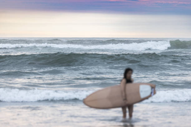 Young lady is surfing on Canggu beach.Bali Island - Indonesia.