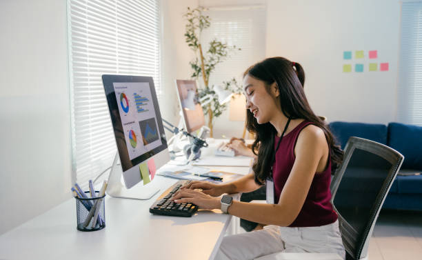 istock Young asian businesswoman sitting and working with computer analyzing charts and graphs showing increase in sales and profit while typing on keyboard at modern office 2194064508
