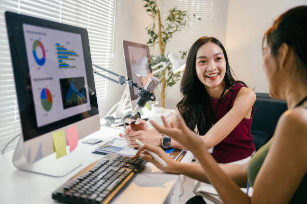 istock Two happy asian businesswomen are discussing charts and graphs displayed on computer screen, collaborating on a project in a modern office environment 2194064531