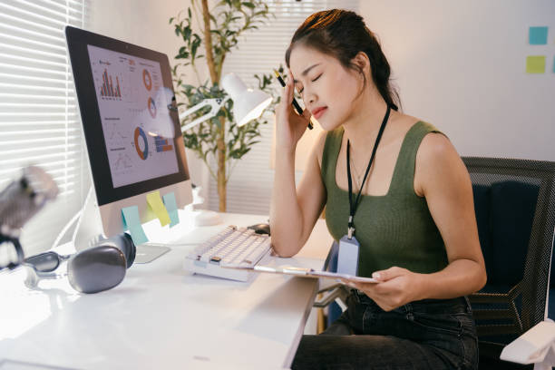 istock Young asian businesswoman massaging her head while working on a computer, experiencing migraine and fatigue from prolonged screen time in the office 2194064617