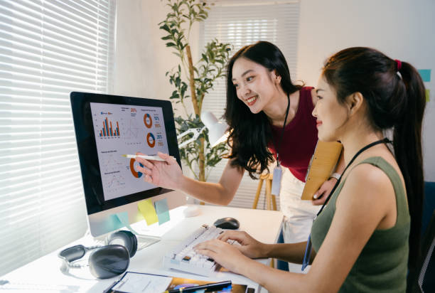 istock Two young businesswomen are collaborating on a project, analyzing charts and graphs on a computer screen in a modern office environment, working together to achieve business success 2194064946