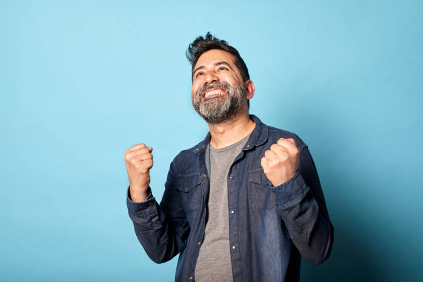 istock Excited Latin Man Celebrating Success with Raised Fists 2194065464