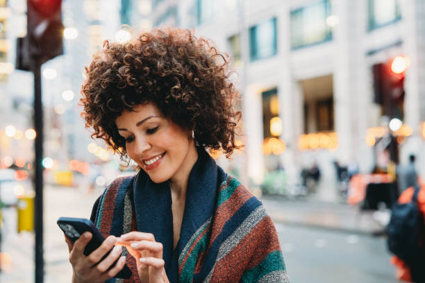 istock Smiling young woman using smartphone on a city street 2194066903