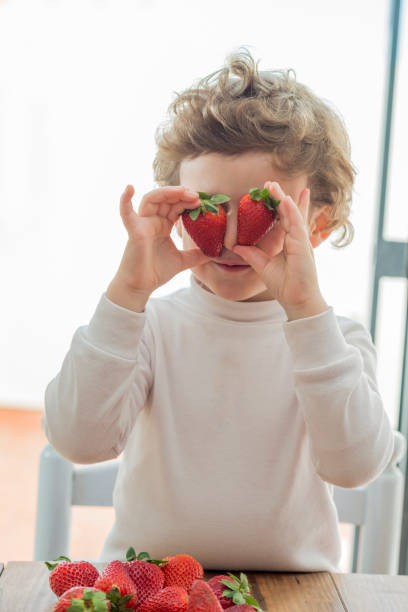 istock Child covering his eyes with two strawberries 2194067145