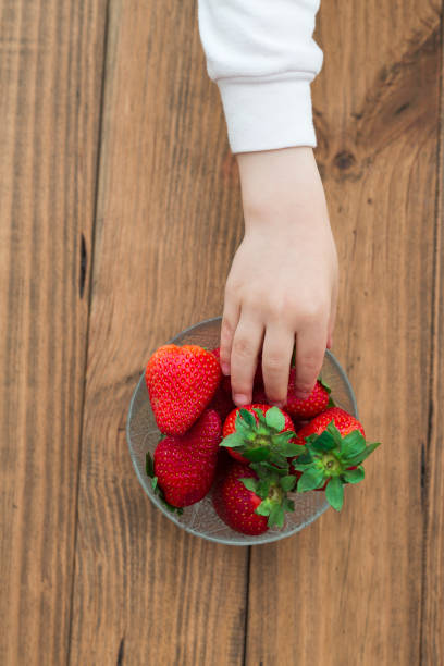 istock Child picking up a strawberry from a bowl 2194067150