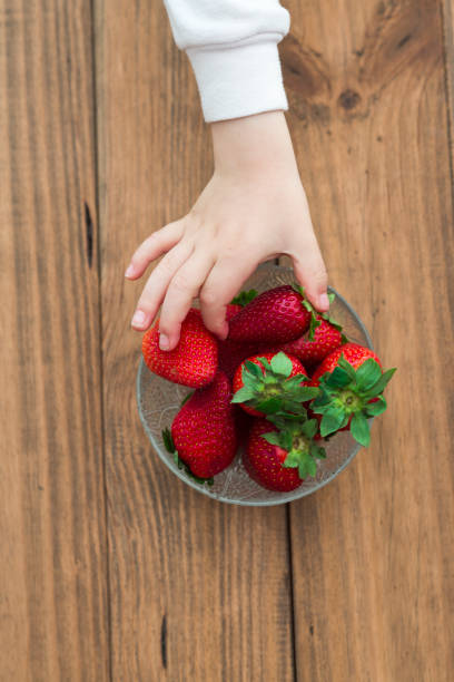 istock Child picking up a strawberry from a bowl 2194067154