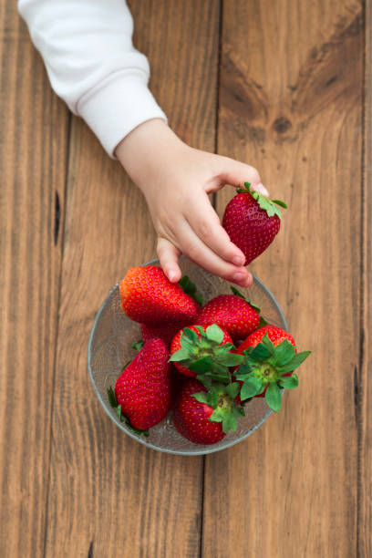 istock Child picking up a strawberry from a bowl 2194067156