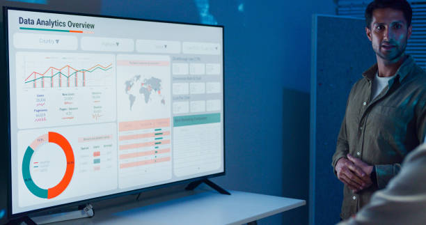 istock Group of business professionals meeting working late discussing strategy and analyzing data on a large screen, collaborating on business growth standing at office night. Finance meeting. 2194068204