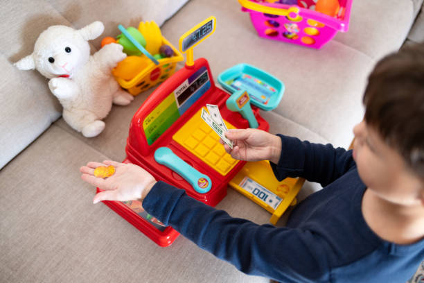 istock A boy is playing store with a toy cash register. 2194071255
