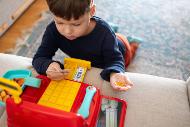 istock A boy is counting toy money while playing with a toy cash register. 2194071264