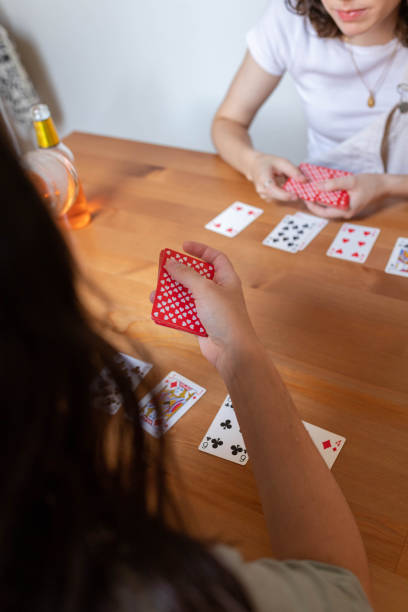 istock Anonymous lesbian couple playing cards at table at home 2194071318