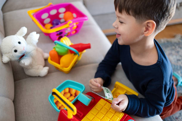 istock A boy is playing store with a toy cash register. 2194071412