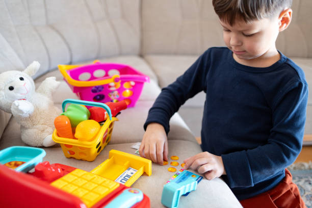 A boy is counting toy money while playing with a toy cash register.