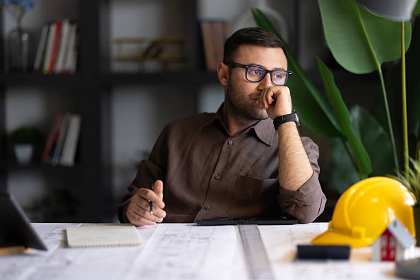 istock Architect man holding pencil working with laptop and blueprints for architectural plan, engineer sketching a construction project concept. 2194074592