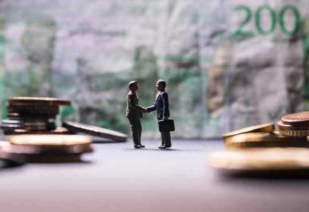 istock Two men shaking hands in front of a large bank note.. 2194074875