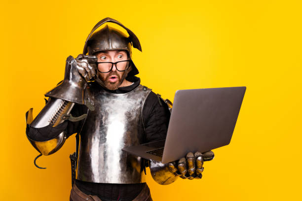 istock Surprised Male in Medieval Armor Using Modern Laptop Against Yellow Background 2194075803