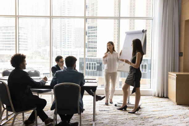 istock Two multiethnic businesswomen make flip chart presentation for shareholders 2194080329