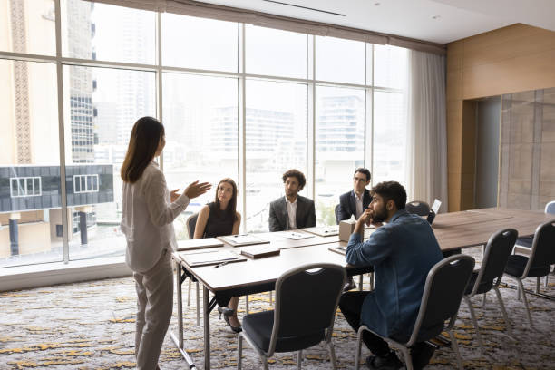 istock Young female coach speaking at diverse corporate group meeting 2194080460
