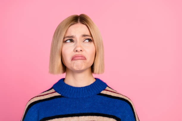 istock Charming young woman with a short bob hairstyle showing a pouting expression against a vibrant pink background 2194081698