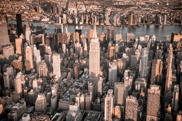 Toned aerial cityscape of Midtown Manhattan with the East River in the background and Queens beyond shot via helicopter from an altitude of about 2000 feet over the city.