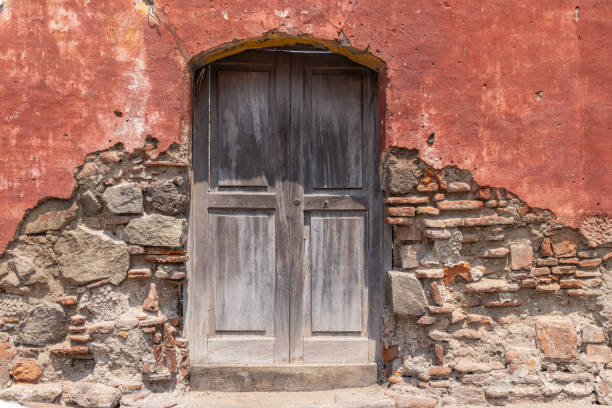 istock Weathered wooden door in a crumbling stucco and stone wall. 2194085015