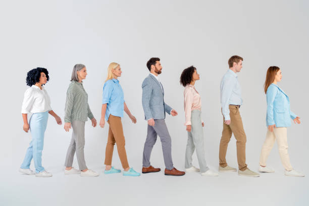 istock Diverse group of professionals walking together with determination on a light grey background, representing teamwork and collaboration 2194086732