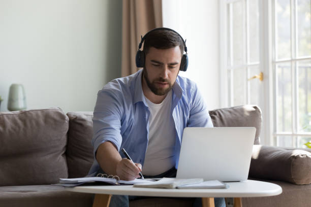 istock Focused serious millennial man in wireless headphones talking video call 2194092855