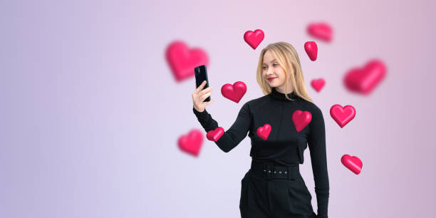 istock Woman taking a selfie with floating hearts on a gradient backgro 2194093221