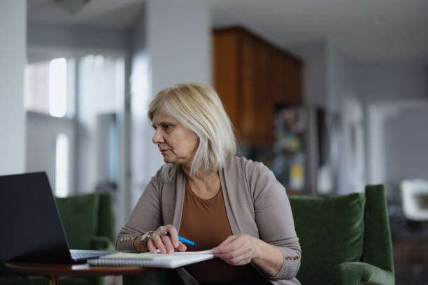 istock Focused Woman Working Remotely at Home Using Laptop and Notebook 2194095171