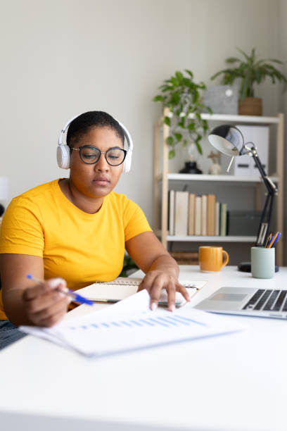 istock Focused young woman working from home office analyzing charts and graphs 2194097267