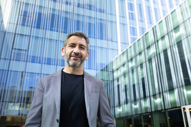 istock Smiling businessman standing in front of modern office building 2194097390