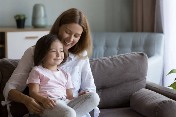 istock Cheerful mom holding happy daughter in arms on sofa 2194099080