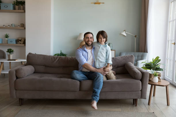 istock Happy handsome dad and little son kid sitting on sofa 2194099186