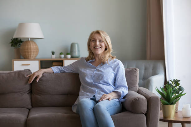 istock Happy blonde mature 50s woman resting on soft couch 2194099507