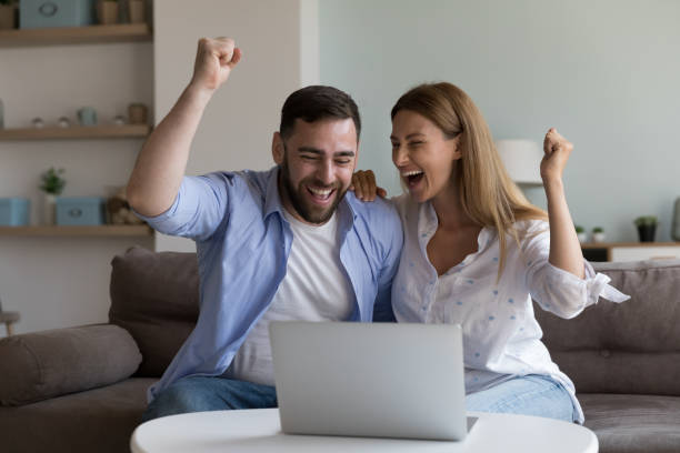 istock Cheerful excited millennial husband and wife making winner yes hands 2194100231