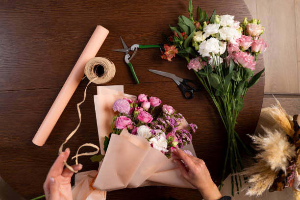 istock Collecting compositions of bloom mixed flowers in the floral studio. Process of assembling a bouquet. Wrapping bouquets of flowers into craft paper by florist. 2194102401
